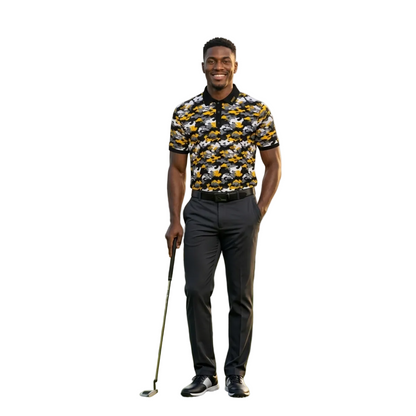 A man stands on a golf course holding a golf club, wearing a short-sleeve polo shirt with a yellow, black, and white patterned design, dark gray trousers, and black and white sneakers.