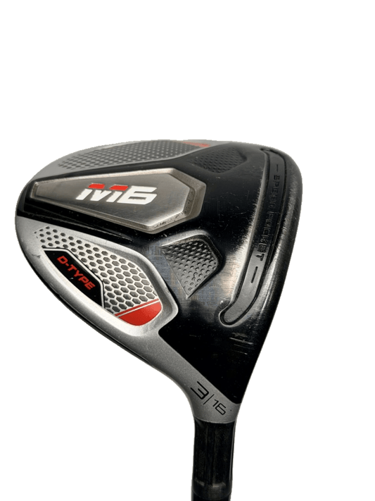 A close-up shot of a golf club head, specifically an M6 driver, featuring a black and silver finish with red accents and the M6 logo, set against a plain white background.
